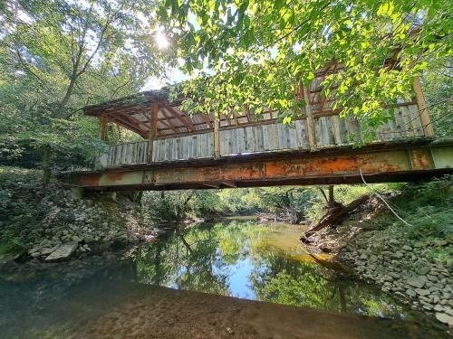 a bridge over a river with a reflection in the water at Covered Bridge Tiny Home Bus On The Water In Rrg in Stanton