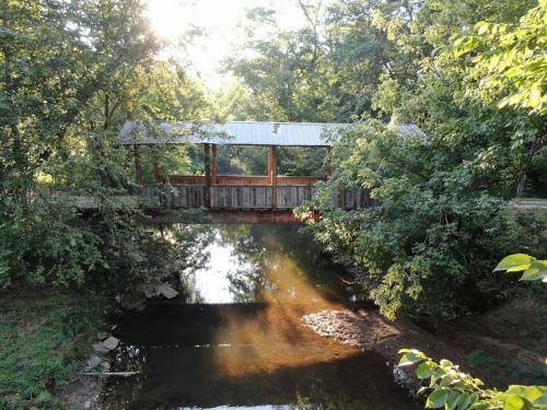 a wooden bridge over a river with a bridge istg at Covered Bridge Tiny Home Bus On The Water In Rrg in Stanton