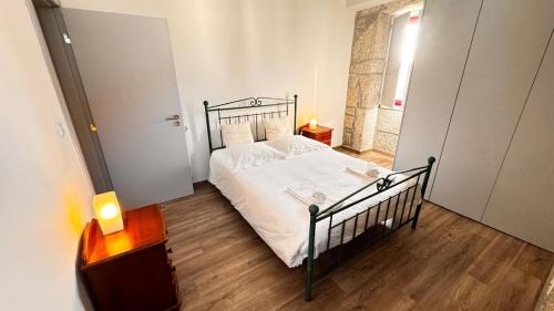 a bedroom with a bed with white sheets and a wooden floor at Casa das Antas in Antas