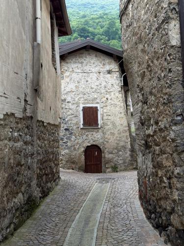 an alley with a stone building with a door at Casa Lagò Lagò Panoramic Apartment in Ranzanico