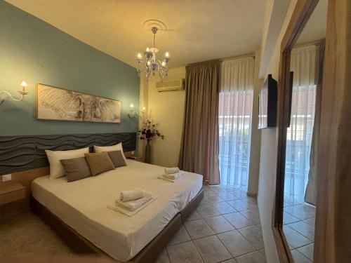a bedroom with a bed and a chandelier at Leonidas Apartments & Suites 2 in Mola Kalyva