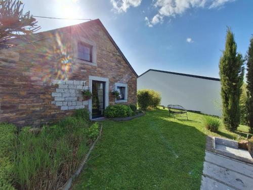 a brick house with a bench in the yard at Le charme des Pierres et wellness in Ohey
