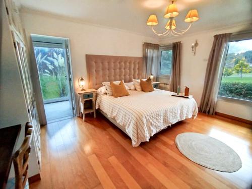 ein Schlafzimmer mit einem großen Bett und zwei Fenstern in der Unterkunft La Aguada in El Bolsón