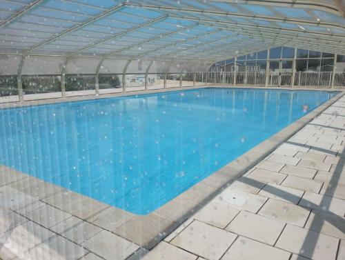 - une vue sur la piscine dotée d'un toit en métal dans l'établissement Chalet avec piscine proche de la plage, à Grandcamp-Maisy