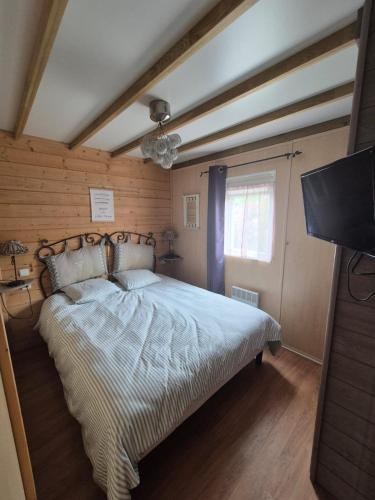une chambre avec un lit et une télévision à écran plat dans l'établissement Chalet avec piscine proche de la plage, à Grandcamp-Maisy