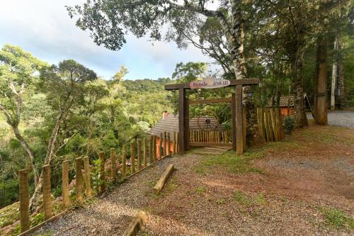 a wooden gate with a sign on it next to a fence at Recanto Lira 1 e 3 in Monte Verde