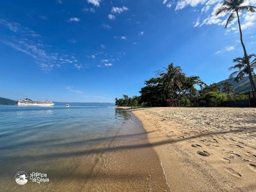 a sandy beach with palm trees and the ocean at Linda suíte à 300m da Praia do Pequeá no Saco da Capela in Ilhabela
