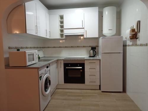 a kitchen with white cabinets and a white refrigerator at Casa Martita in Torrevieja