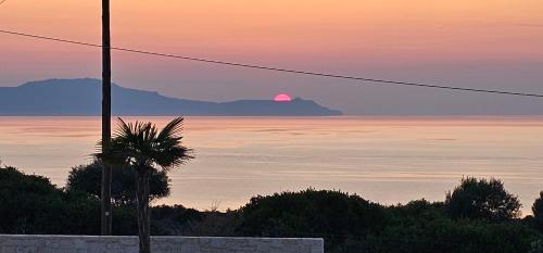 a sunset over the ocean with a mountain in the background at Luxurious Villas Rocca Blanco 1 & 2 in Kounoupidhianá