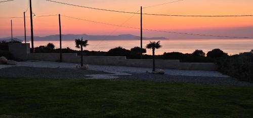 a sunset with two palm trees in a field at Luxurious Villas Rocca Blanco 1 & 2 in Kounoupidhianá