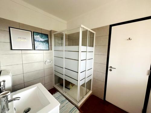 a bathroom with a sink and a glass shower at Casinha do Amor in Guia