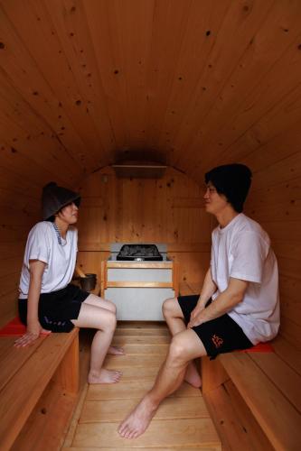 a couple of people sitting in a sauna at Guesthouse Fukufuku in Tanabe
