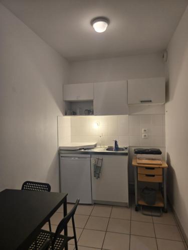 une cuisine avec des armoires blanches et une table avec des chaises dans l'établissement Terracotta, à Lyon