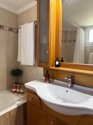 a bathroom with a sink and a mirror and a tub at Nostos Apartment Galatas in Galatas