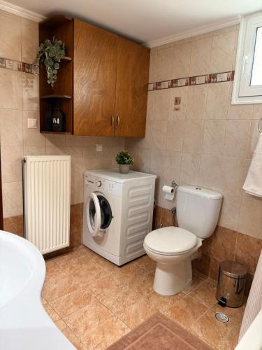 a bathroom with a toilet and a washing machine at Nostos Apartment Galatas in Galatas