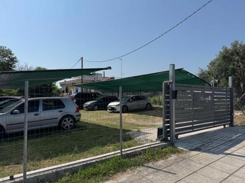 a fence with cars parked in a parking lot at Amaryllis House in Platamonas