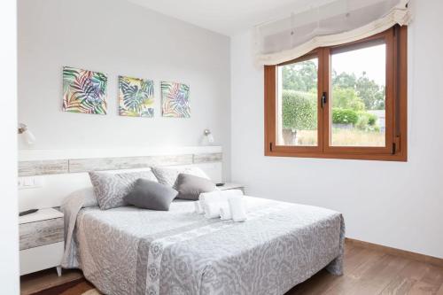 a white bedroom with a bed and a window at A Raxeira de Jose in Campañó