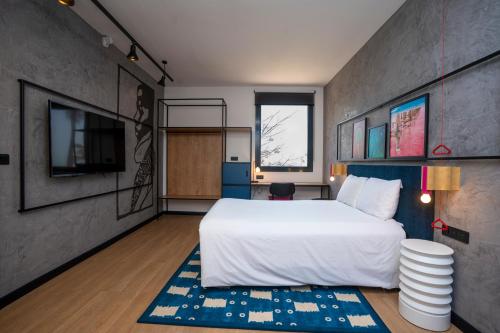 a bedroom with a large white bed and a tv at Ibis Styles Dakar in Dakar