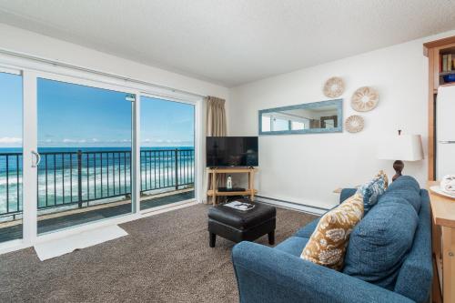 a living room with a blue couch and a large window at Ocean Terrace Condominiums in Lincoln City