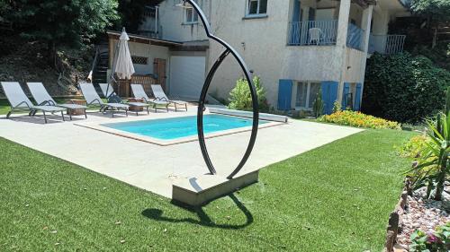 une sculpture en métal dans l'herbe à côté d'une piscine dans l'établissement Maison La Rascasse, à Rayol-Canadel-sur-Mer