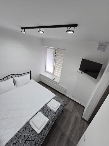 a white bedroom with a bed and a tv at Small House ApartHotel in Chişinău