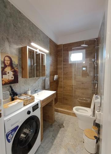 a bathroom with a washing machine in a sink and a toilet at 3B House in Nea Vrasna