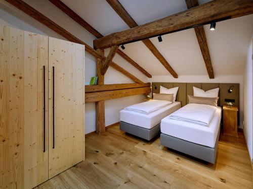 two beds in a room with wooden walls and wooden floors at Moierhof in Gstadt am Chiemsee
