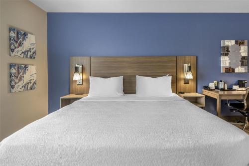 a bedroom with a large bed and a blue wall at Best Western Plus Castlerock Inn & Suites in Bentonville
