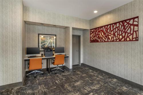 an office with two desks with two computers and orange chairs at Best Western Plus Castlerock Inn & Suites in Bentonville