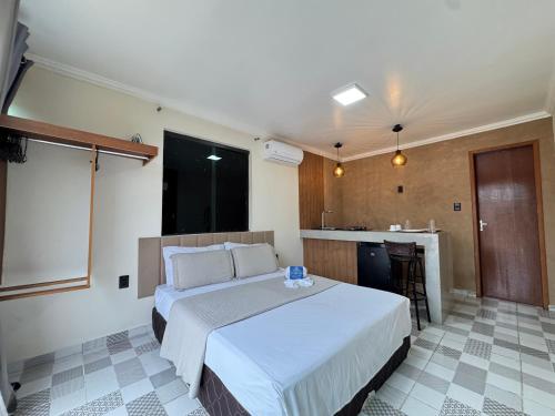 a bedroom with a large bed and a kitchen at BayShore Loft in Cabo Frio