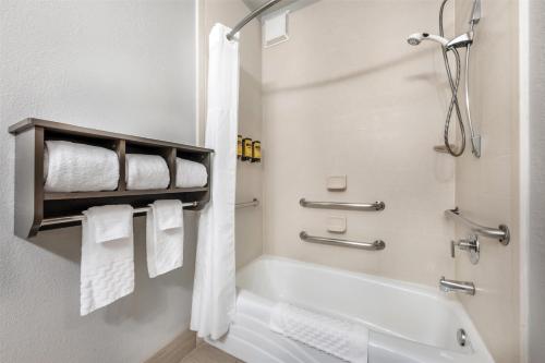 a bathroom with a tub and a shower with towels at Garner Hotel Liberal North by IHG in Liberal