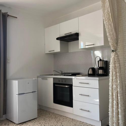 une cuisine avec des armoires blanches et un four à plaques de cuisson dans l'établissement Studio avec terrasse vue Larzac, à Saint-Jean-de-la-Blaquière