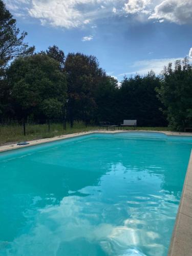 un bassin d'eau bleue avec des arbres en arrière-plan dans l'établissement Dépendance paisible, à Ventenac-Cabardès