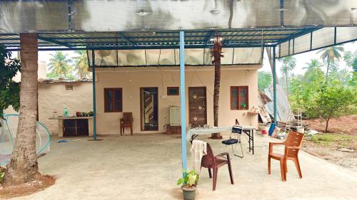 a house with chairs and a table in front of it at Oasis Farm Stay in Bengaluru