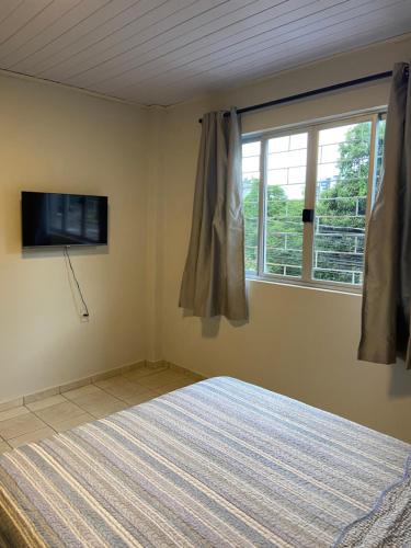 a bedroom with a bed and a window at Studio BIA in Tubarão