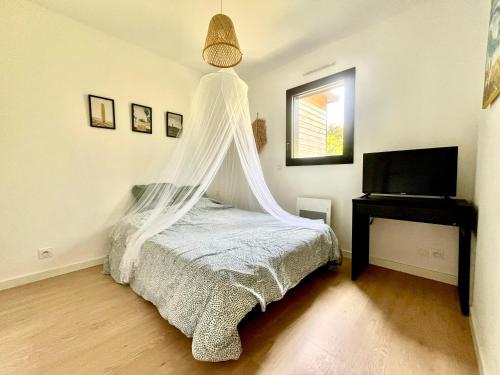 une chambre avec un lit avec moustiquaire dans l'établissement SOZEN - Maison bois récente, lumineuse avec terrasse et grand Jardin, proche des plages, à Tréogat