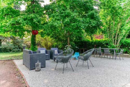 un groupe de chaises et de tables dans un jardin dans l'établissement Villa Les sabines - Welkeys, à Écully