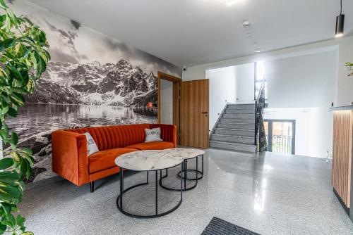 a living room with a orange couch and a table at Perła Tatr - Noclegi z widokiem na góry in Zakopane