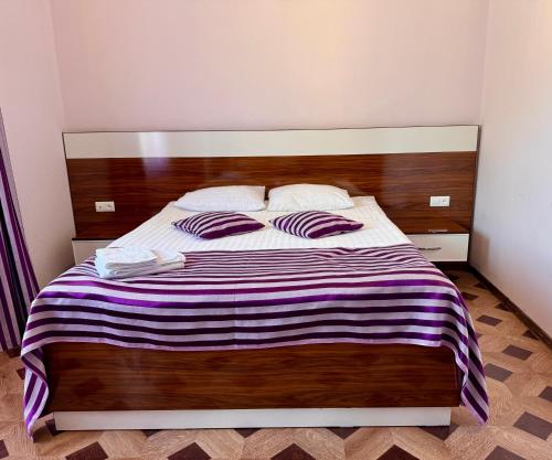 a bed with a wooden headboard and two pillows at Kirch Hotel & Restaurant in Goris