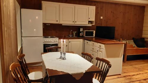 a kitchen with white cabinets and a table with chairs at Trivelig Stabbur på Lånke Gård 