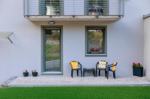 three chairs and a table in front of a house at Revo Apartments - Campelli in Albosaggia