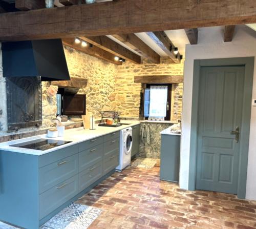 a kitchen with blue cabinets and a washer at La cabaña de San Pelayo in San Pelayo