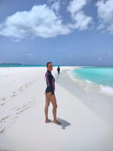 a woman standing on a beach in the ocean at Madi Beach Guesthouse in Maalhos