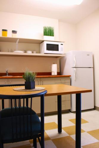 a kitchen with a table and a refrigerator at Hôtel Résidence de La Cité in Ottawa