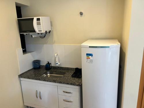 a small kitchen with a refrigerator and a microwave at Hotel Bienal Ibirapuera UH310 in Sao Paulo