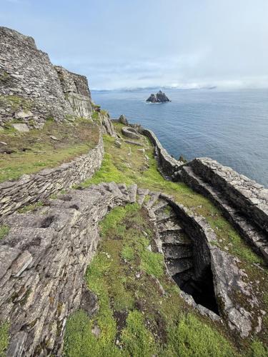 a cave in the side of a cliff next to the ocean at Private Room in Skellig Apartment in Portmagee
