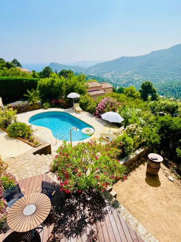 - une vue sur la piscine bordée de parasols et de fleurs dans l'établissement Stunning Villa with Pool, Sea View & Petanque in Golfe Saint Tropez, à Rayol-Canadel-sur-Mer
