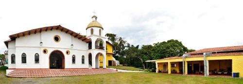 a white church with a steeple next to a building at San Agustin Internacional Hotel in San Agustín