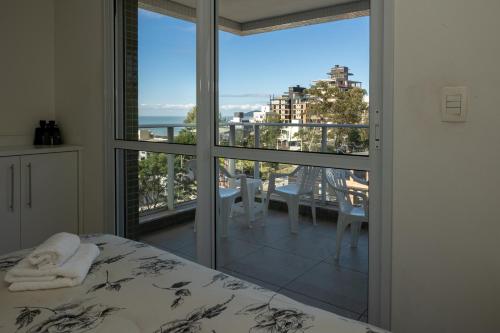 a bedroom with a bed and a view of a balcony at Apto Amores da Brava Clube House - Vista, Piscina e Conforto in Itajaí