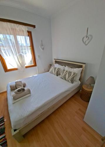 a bedroom with a bed with white sheets and a window at SOFIA'S HOUSE No 2 in LESVOS in Apidias Lakos